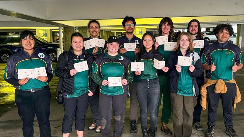 Ten members of the archery club in uniform holding certificates.