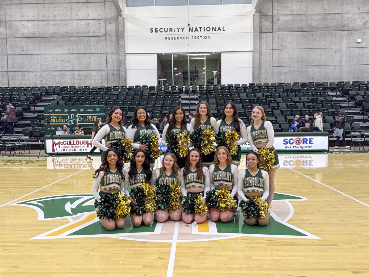 Cheer team photo in their uniforms and pom poms at center court.