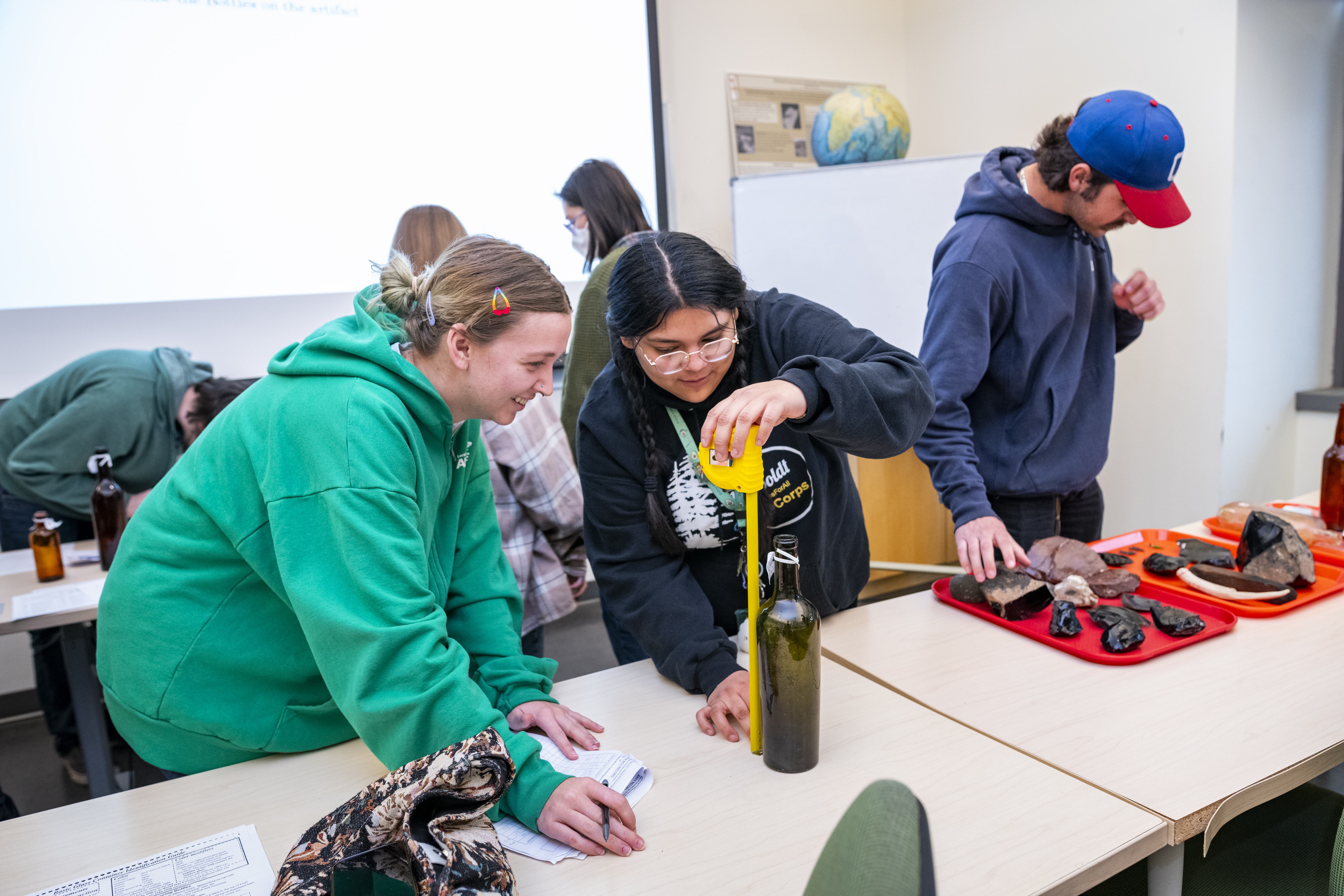 Three students in the Cultural Resources Facility with artifacts.