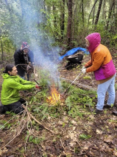 Three students making a fire in the forest.
