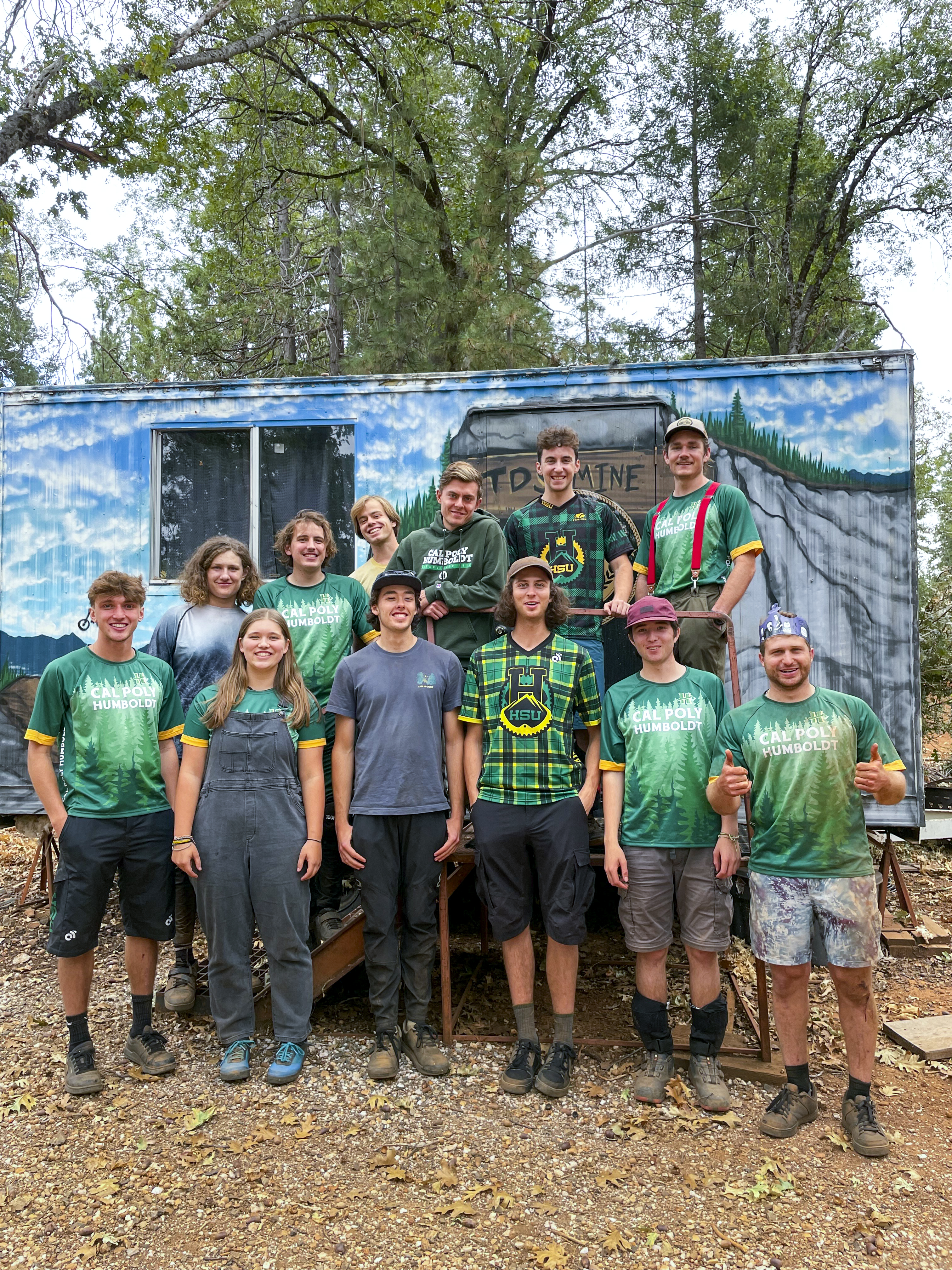 Cycling club group photo in their jerseys outside of a trailer.