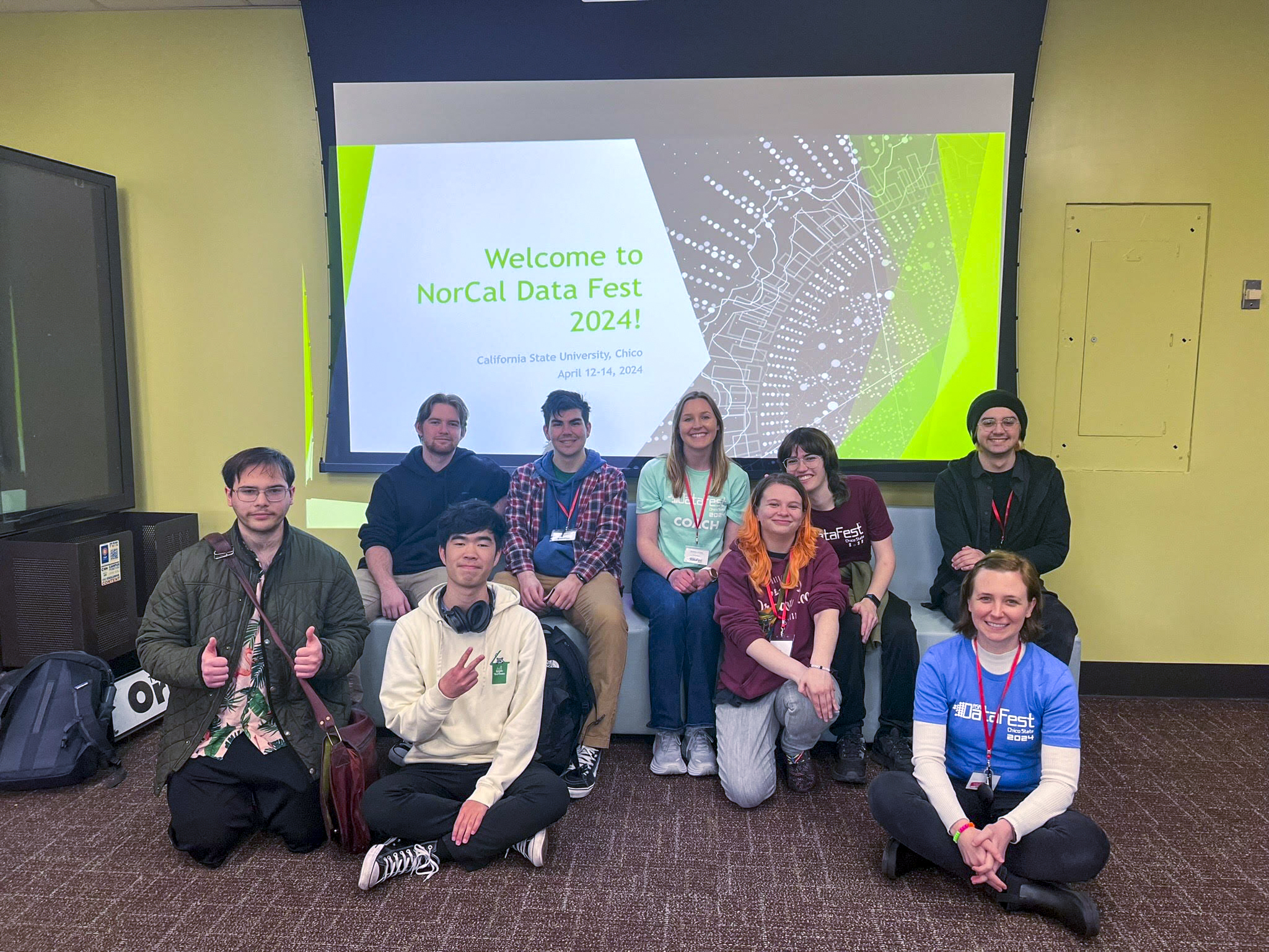 A group of data science students in front of a screen for NorCal Data Fest. 