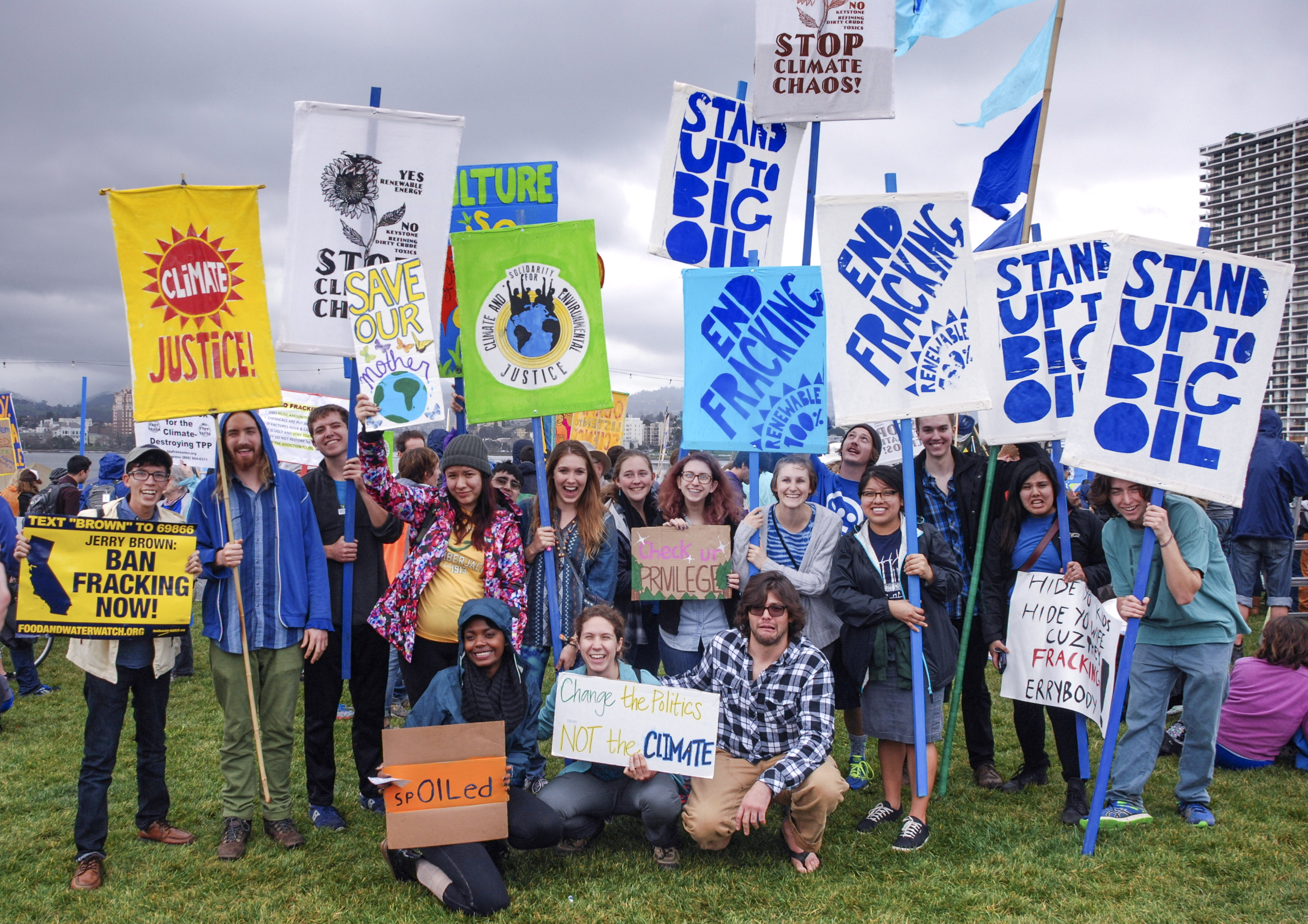 A large group of students with climate protest signs in the air at a rally.