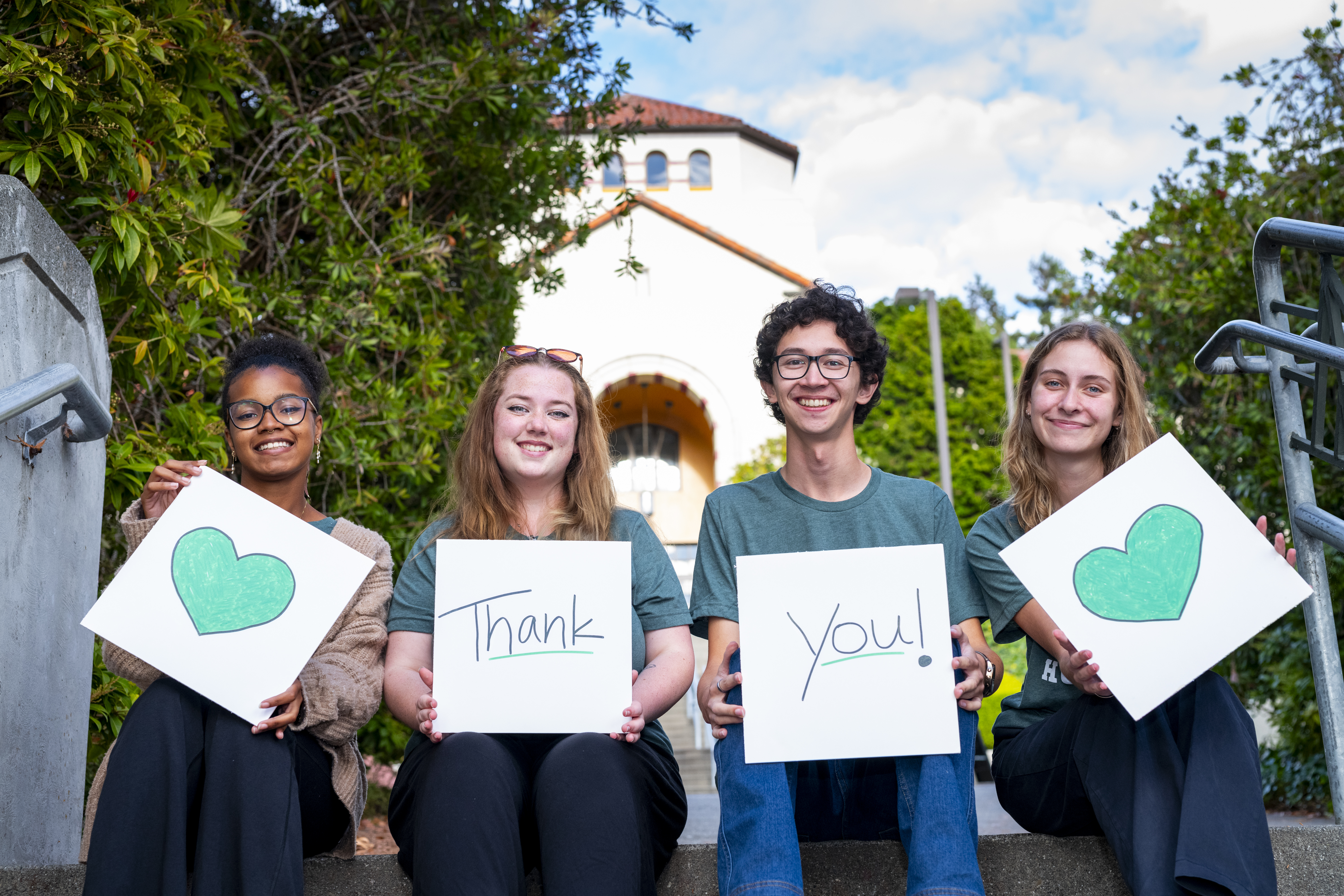 Four students smiling holding a thank you sign.