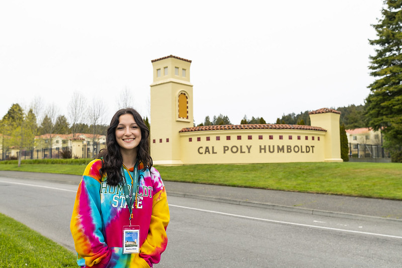 A student standing in front of the Cal Poly Humboldt entry way.