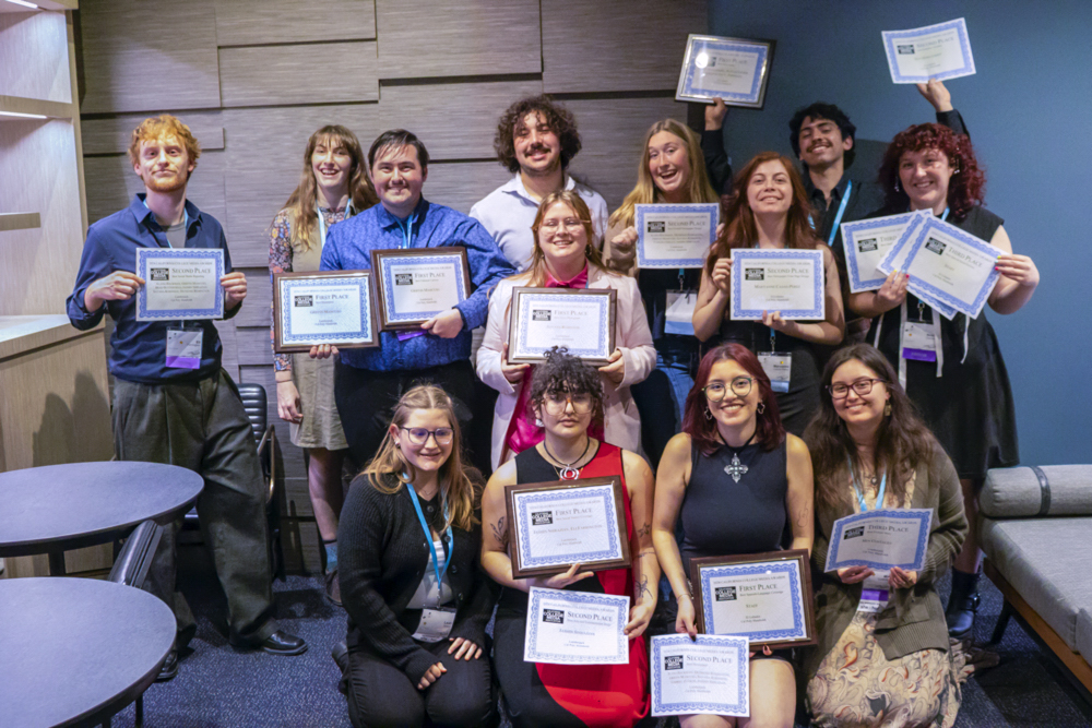A group photo of journalism students smiling and holding certificates.