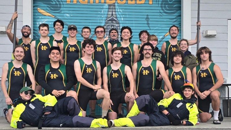 Team photo of the Humboldt men's rowing team in front of their boathouse.