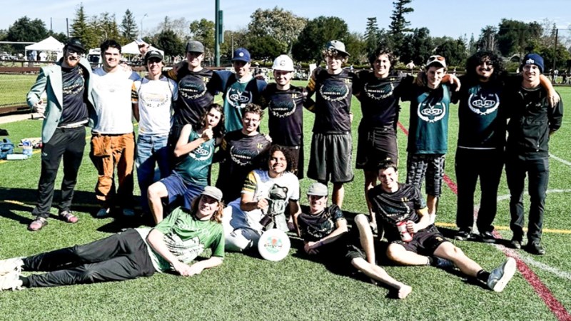 17 men's Ultimate Frisbee members posing on a field with a frog statue.