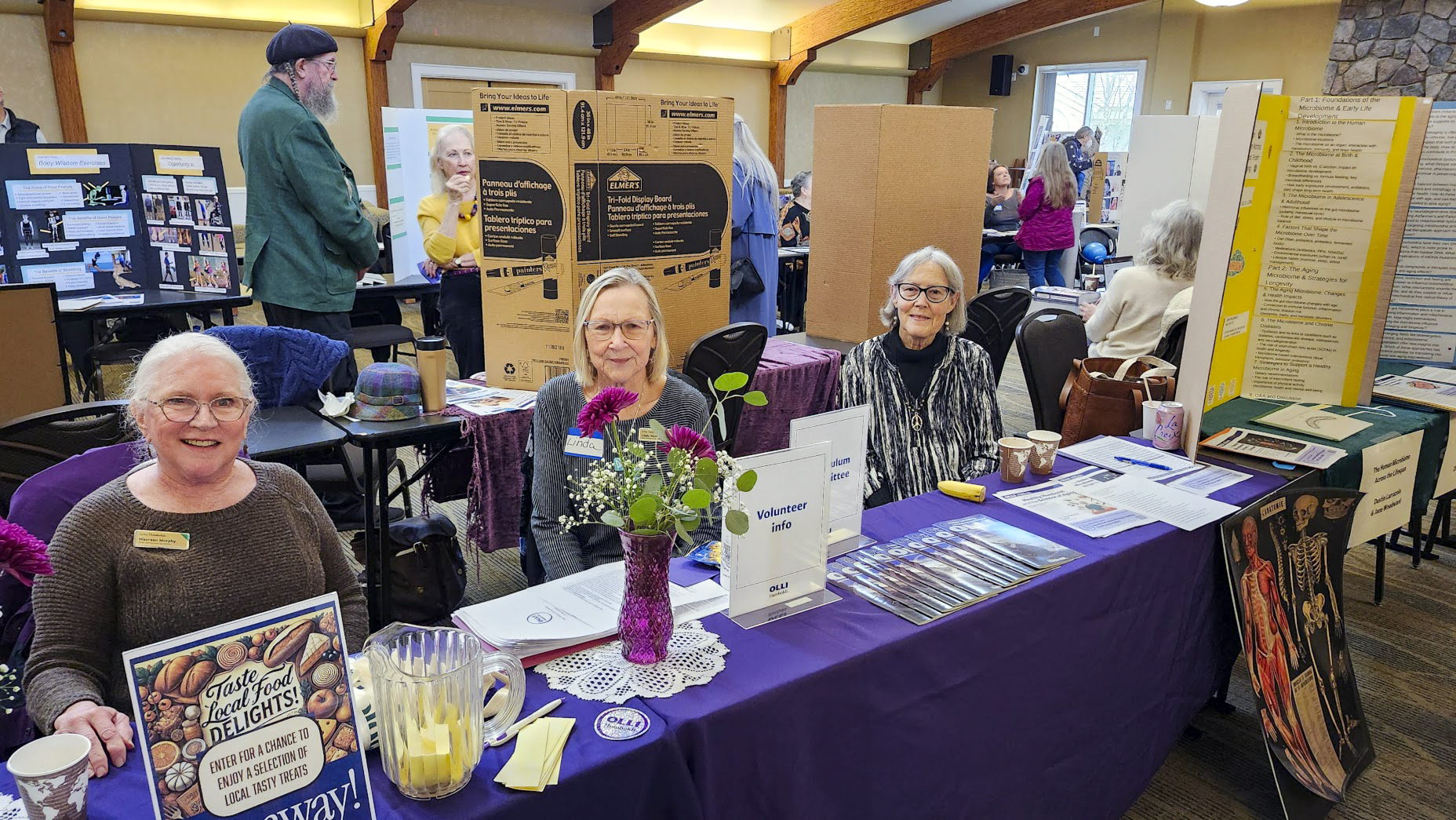 Three OLLI members behind a table doing outreach for the program.