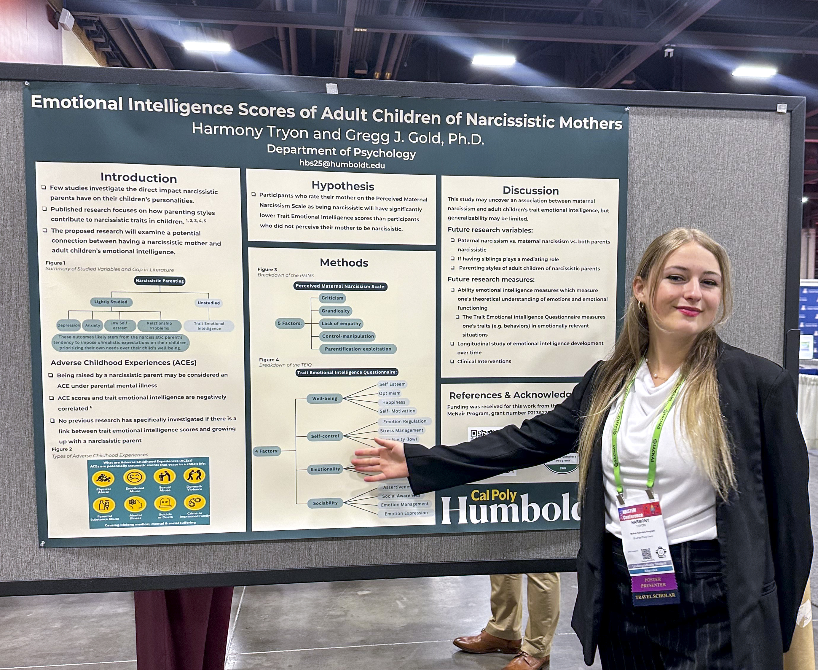 A smiling student in front of an emotional intelligence poster presentation.