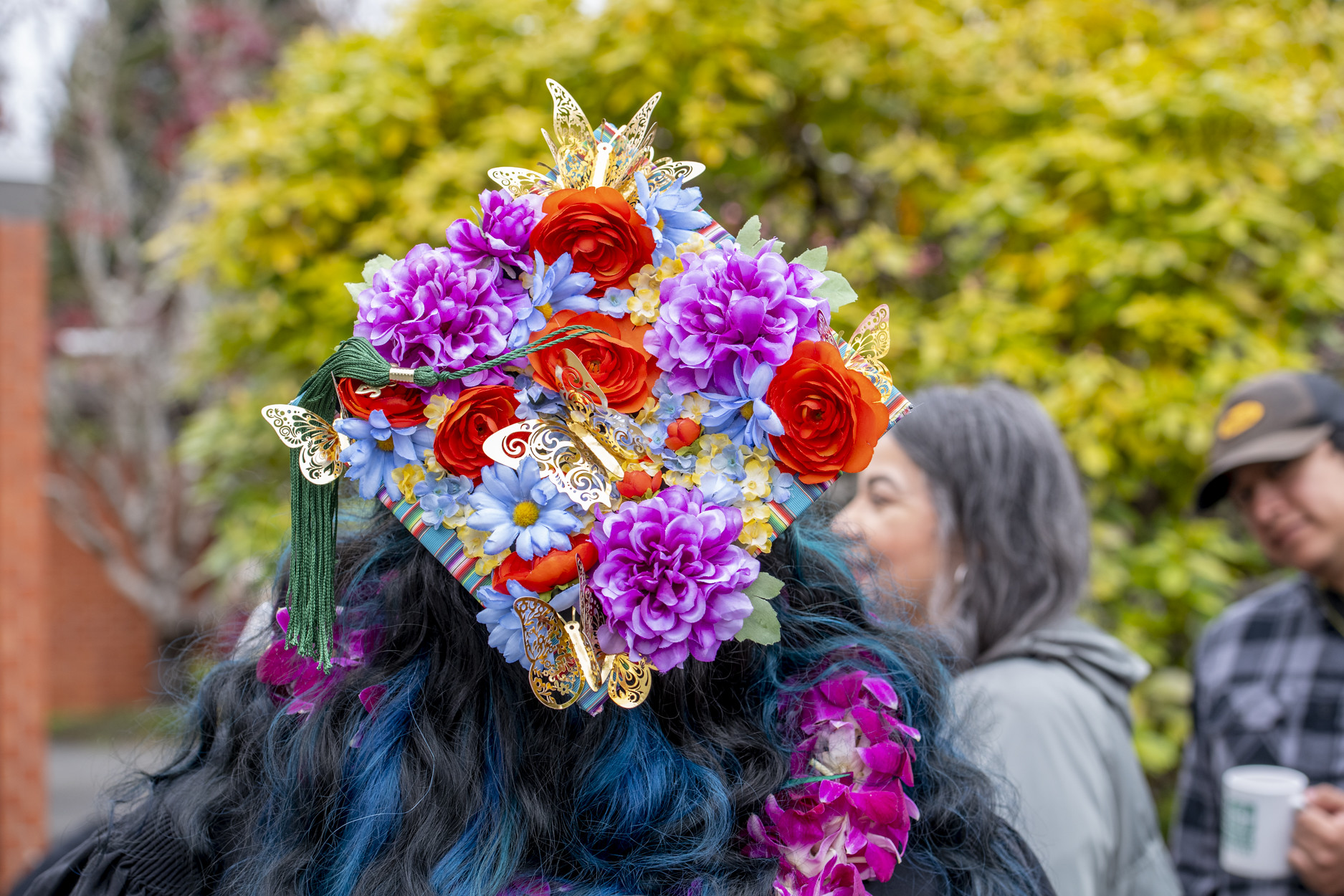 A graduation cap decorated in bright flowers and butterflies.