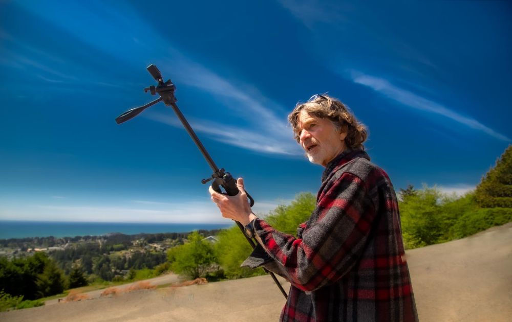 A photo of Ray Olson holding a tripod while filming an episode of Humboldt Outdoors.