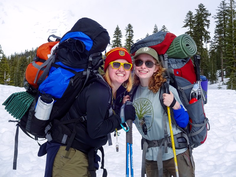 Two smiling outdoor recreation students smiling in their snow backpacking gear.
