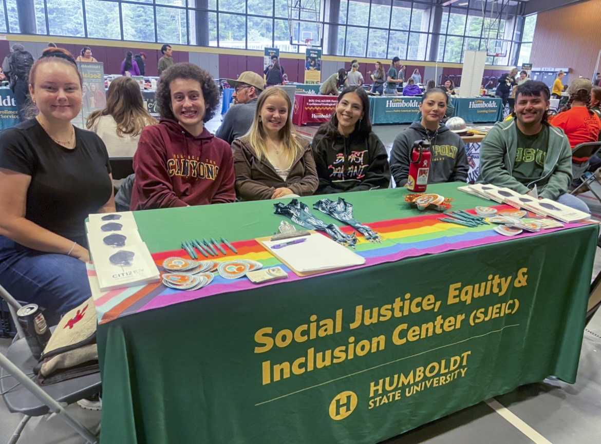 Six students smiling at an outreach table for the SJEIC.