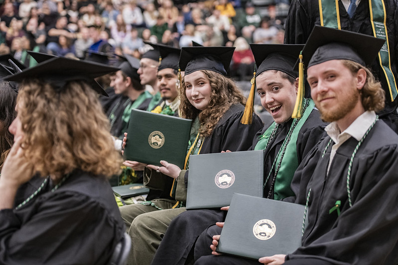 Students at Graduation in their robes showing their diplomas.