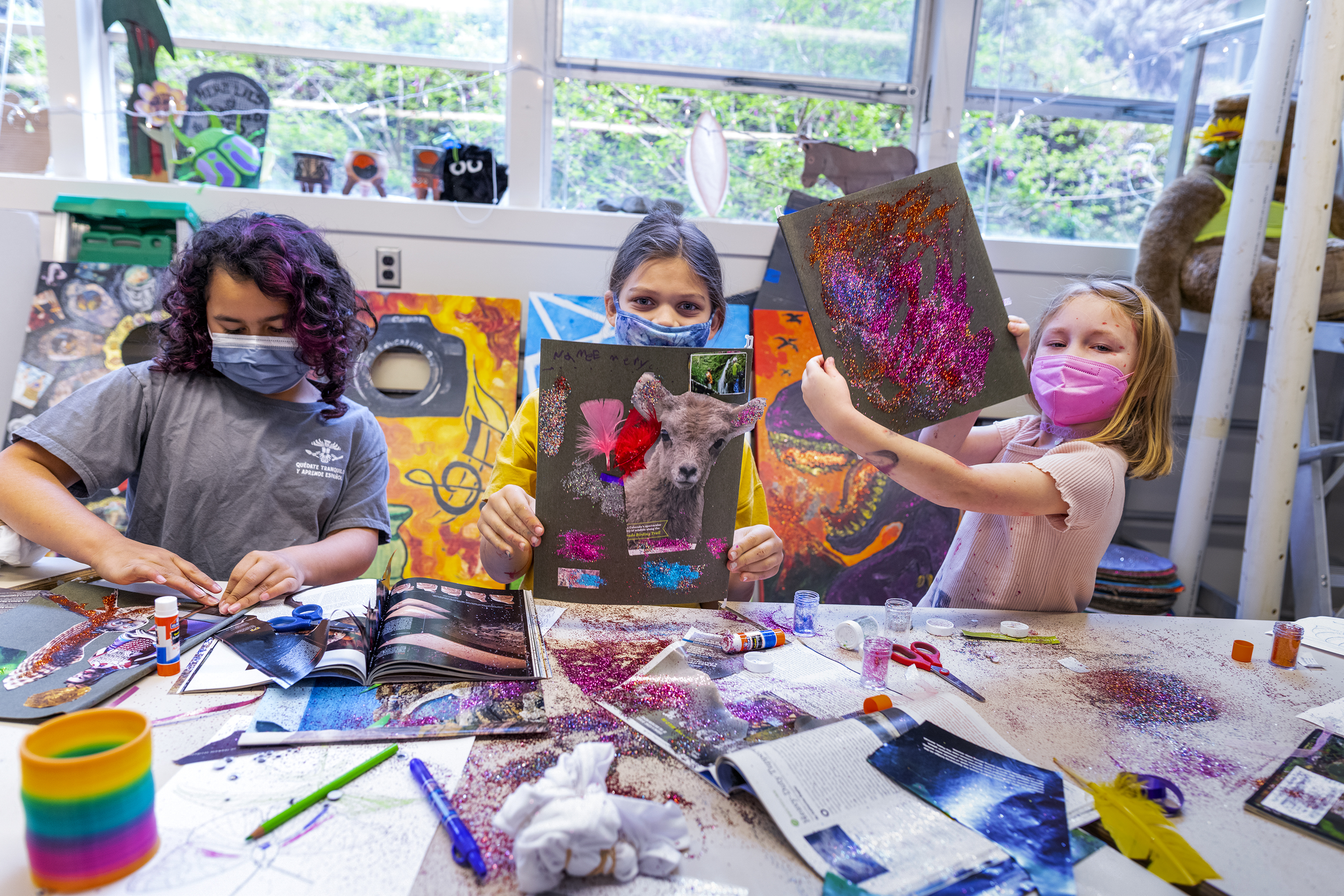 Three kids making art with lots of color and glitter.