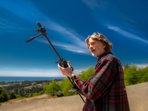 A photo of Ray Olson holding a tripod while filming an episode of Humboldt Outdoors.