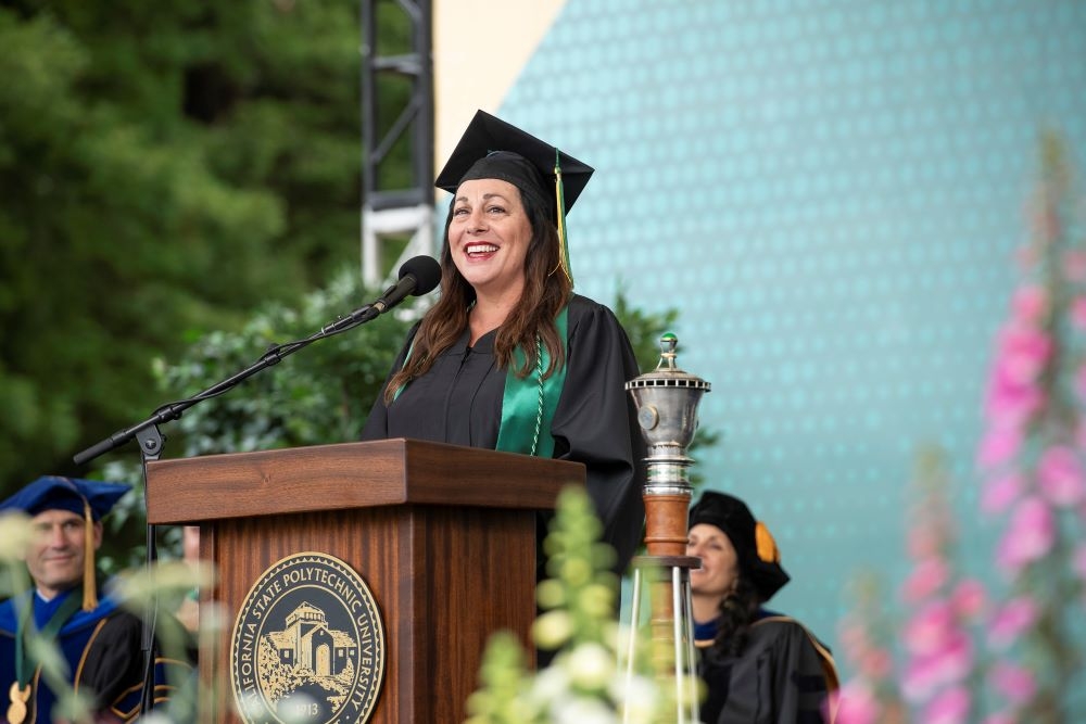 A photo of Cassandra Hesseltine standing at a podium during Spring 2025 Commencement in May. 
